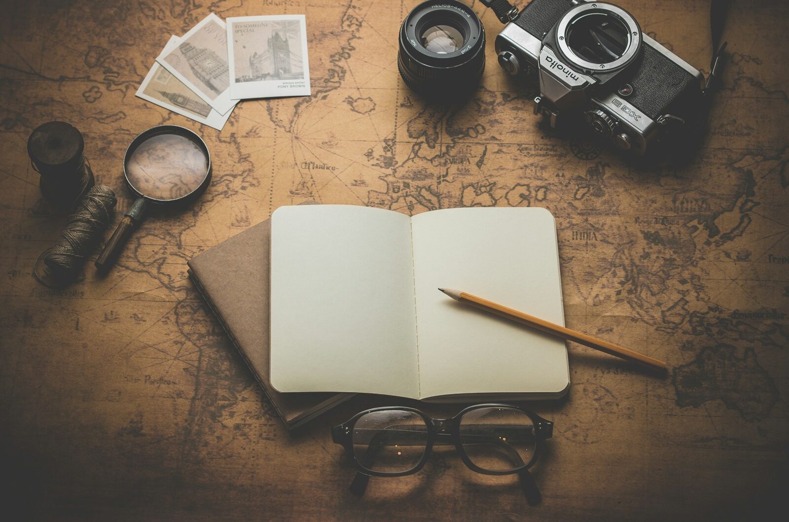 flat ray photography of book, pencil, camera, and with lens