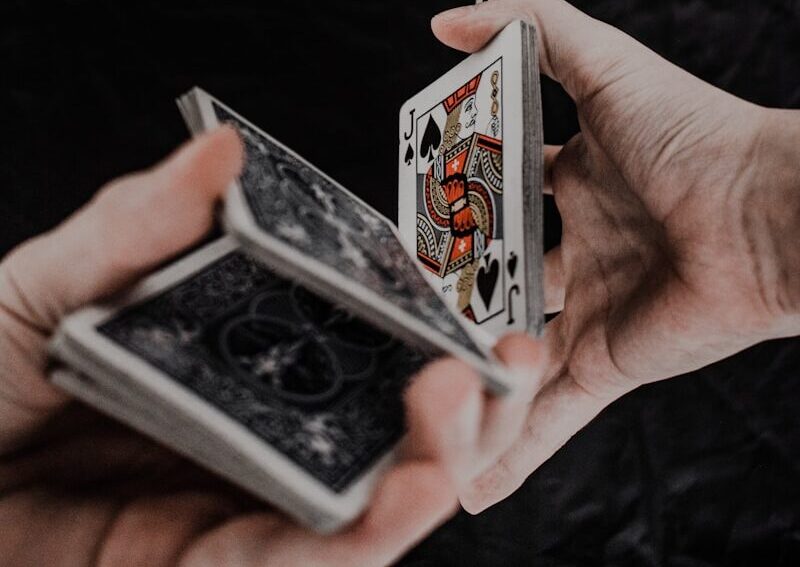 person holding playing cards on black textile